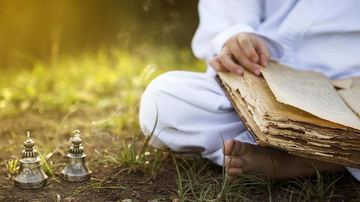 Yogi sitzt auf dem Gras und liest ein Buch über Ayurveda