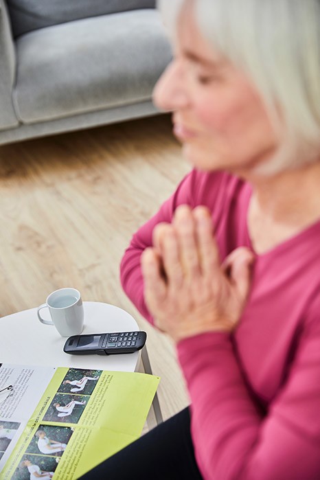 yogafueralle_OMY_telefonyoga 3 Eine alte Dame formt mit ihren Händen eine Mudra, sie macht Telefonyoga