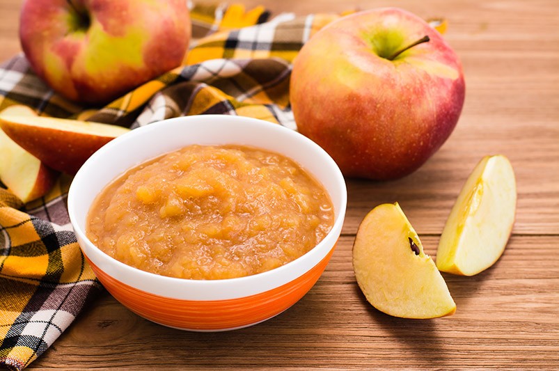 Apfelmus Neben einer Schüssel mit Apfelmus liegen Äpfel. Apfelmus ist eine tolle Ei-Alternative