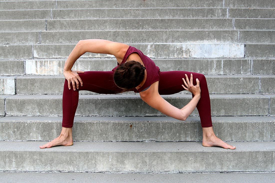 Frau steht auf Treppenstufen und führt eine Yogapose aus, dies ist gut für die Faszien