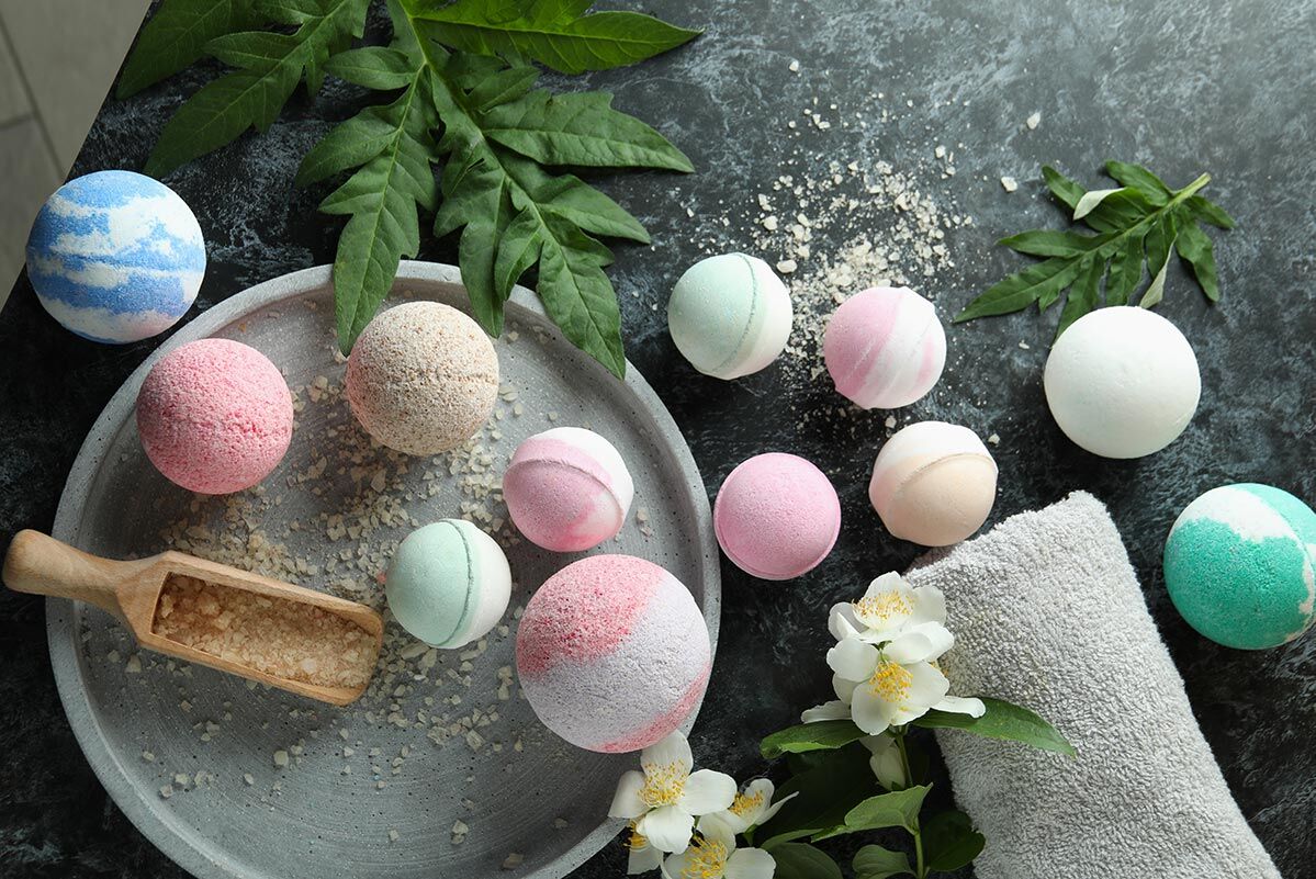 Badekugeln viele bunte Badekugeln liegen auf einer Marmorfläche. Dort liegen auch ein Handtuch, Pflanzen und Badesalz