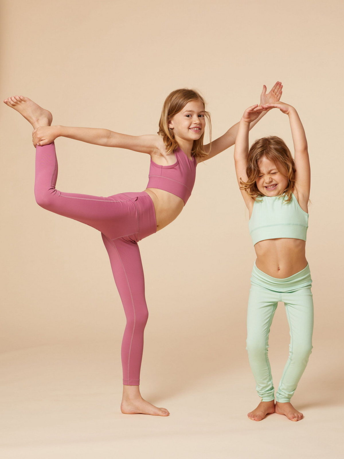 Zwei Mädchen tragen Yogaoutfits im Partnerlook und turnen darin herum