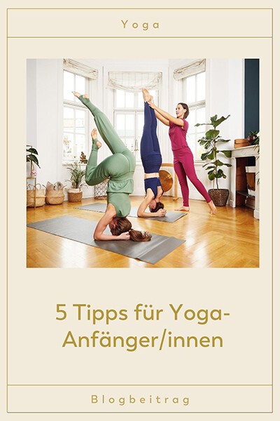 5 Tipps für Yoga-Anfängerinnen Zwei Yogis üben einen Kopfstand, eine weitere Yogini hilft ihnen dabei