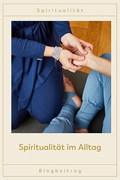 Spiritualität im Alltag Eine Yogini betastet die Hand einer anderen Frau. Sie trägt eine Mala um das Handgelenk und übt Spiritualität im Alltag.