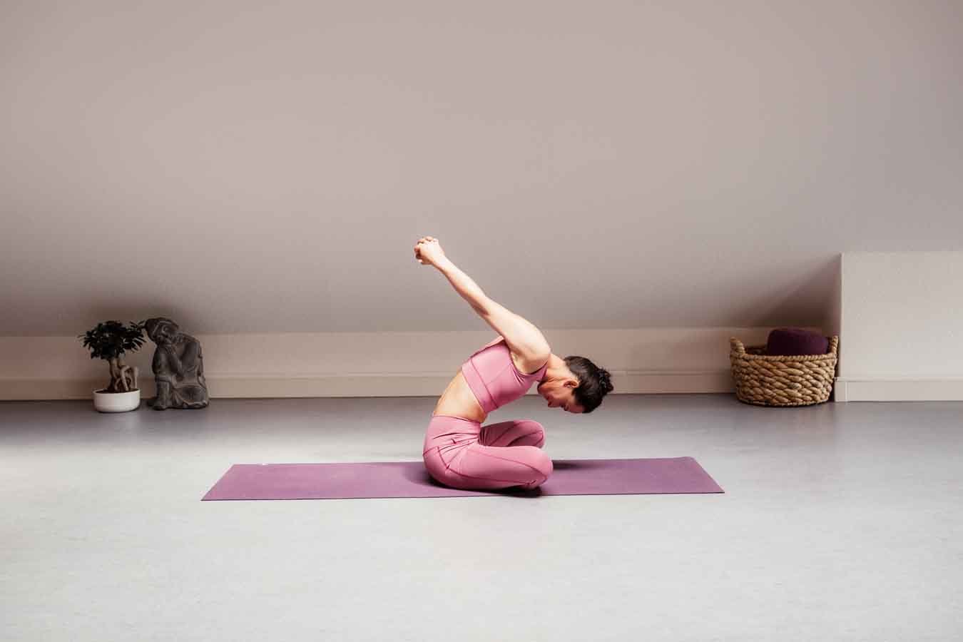 Frau sitzt im Schneidersitz auf einer Yogamatte in einem Yogastudio und macht Yoga für die Organe.